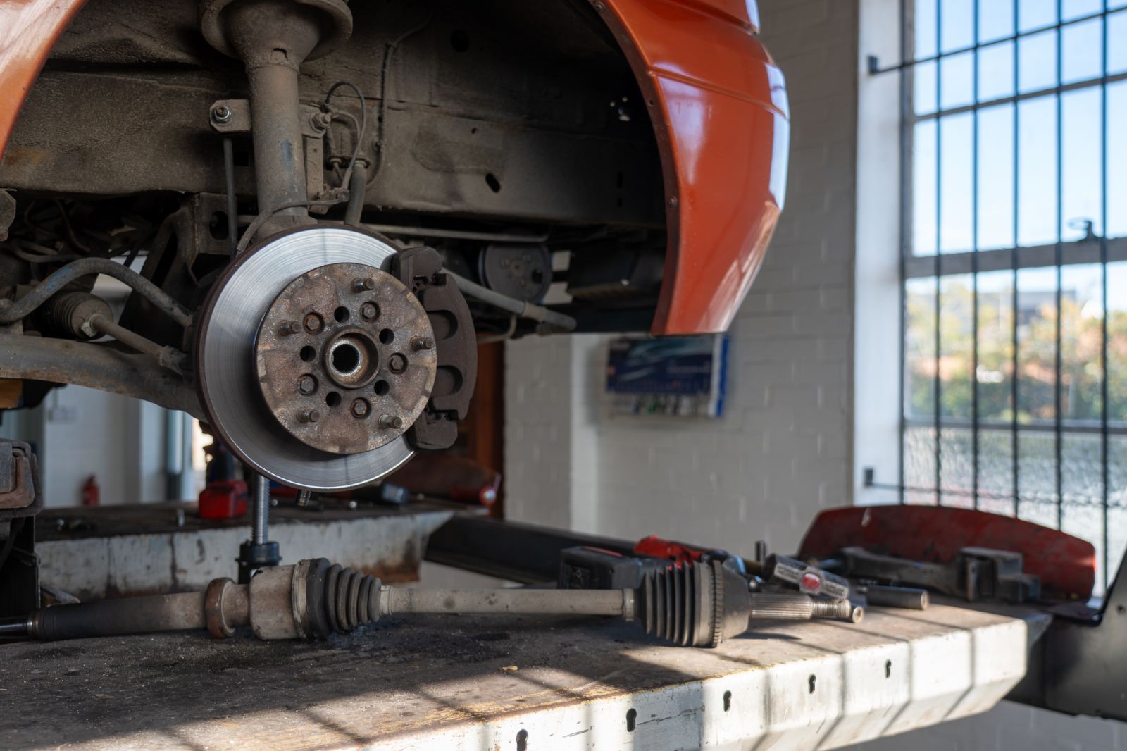 A brake disc and hub on a van, with a driveshaft on the bench in front