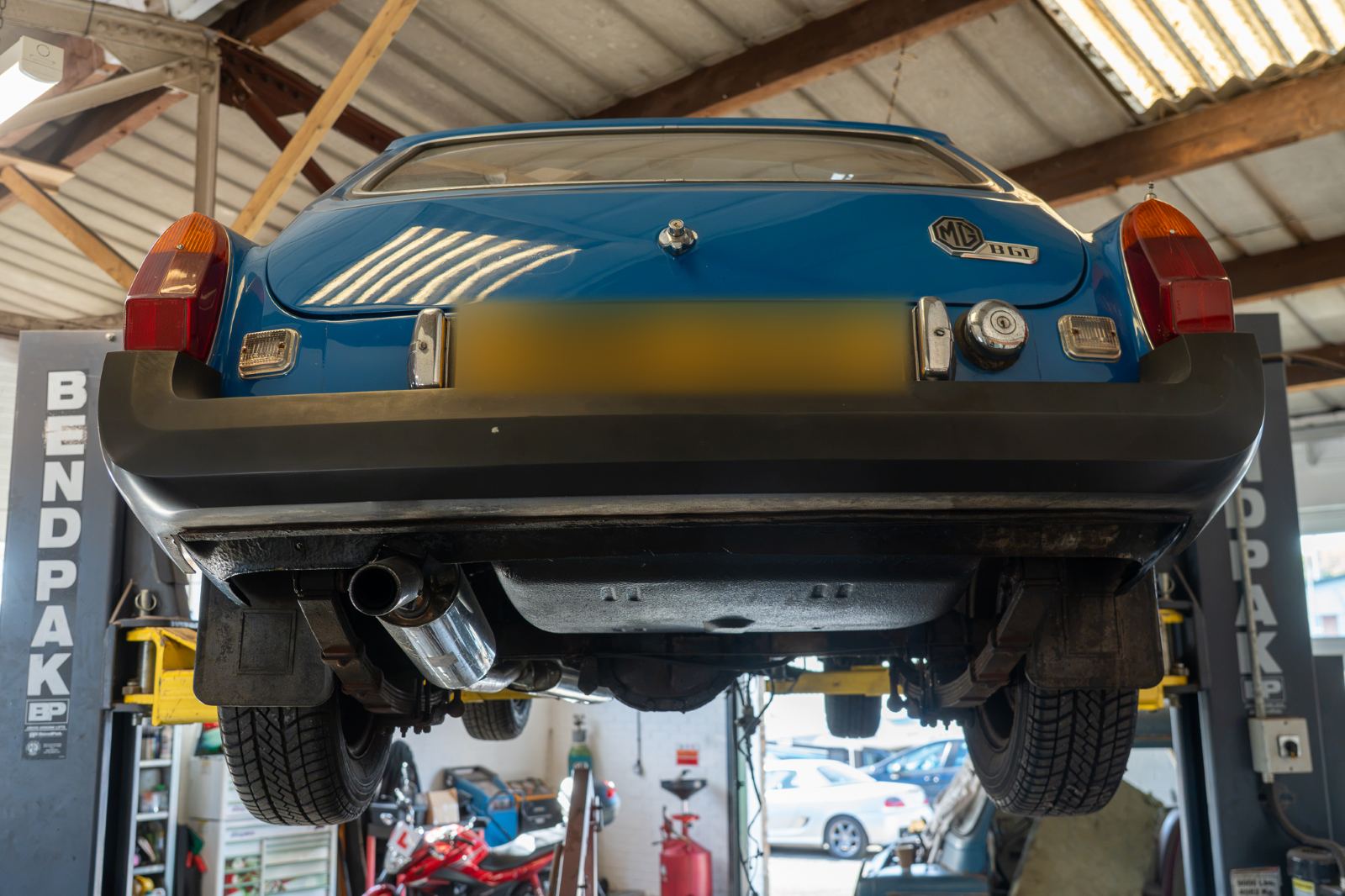 The rear and underside of a blue MG raised on the lift